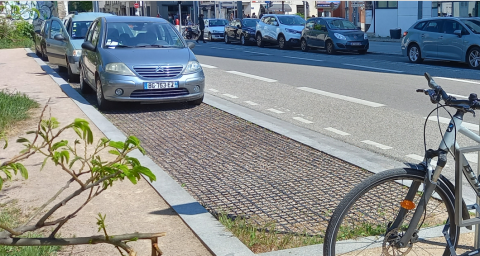 Emplacement de stationnement en dalles PVC alvéolées avec un remplissage gravier. Le trottoir exposé au soleil aux heures les plus chaudes est en sable stabilisé tandis que celui situé à l’ombre du bâtiment est en asphalte. Pour respecter les exigences d’